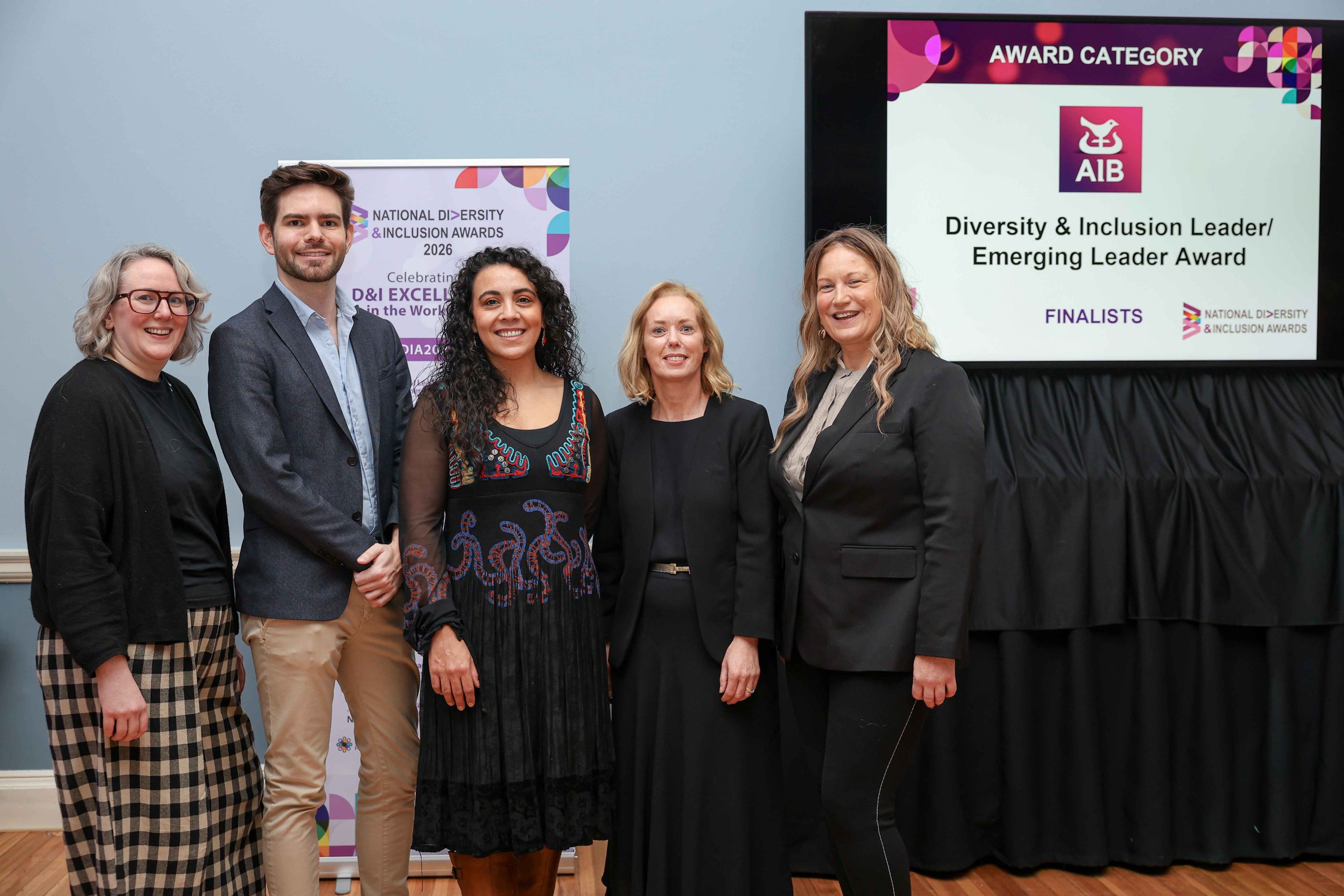 5 smiling people standing shoulder to shoulder