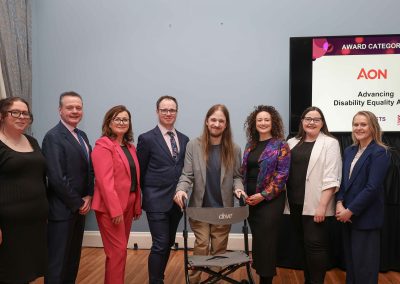 8 smiling people standing shoulder to shoulder