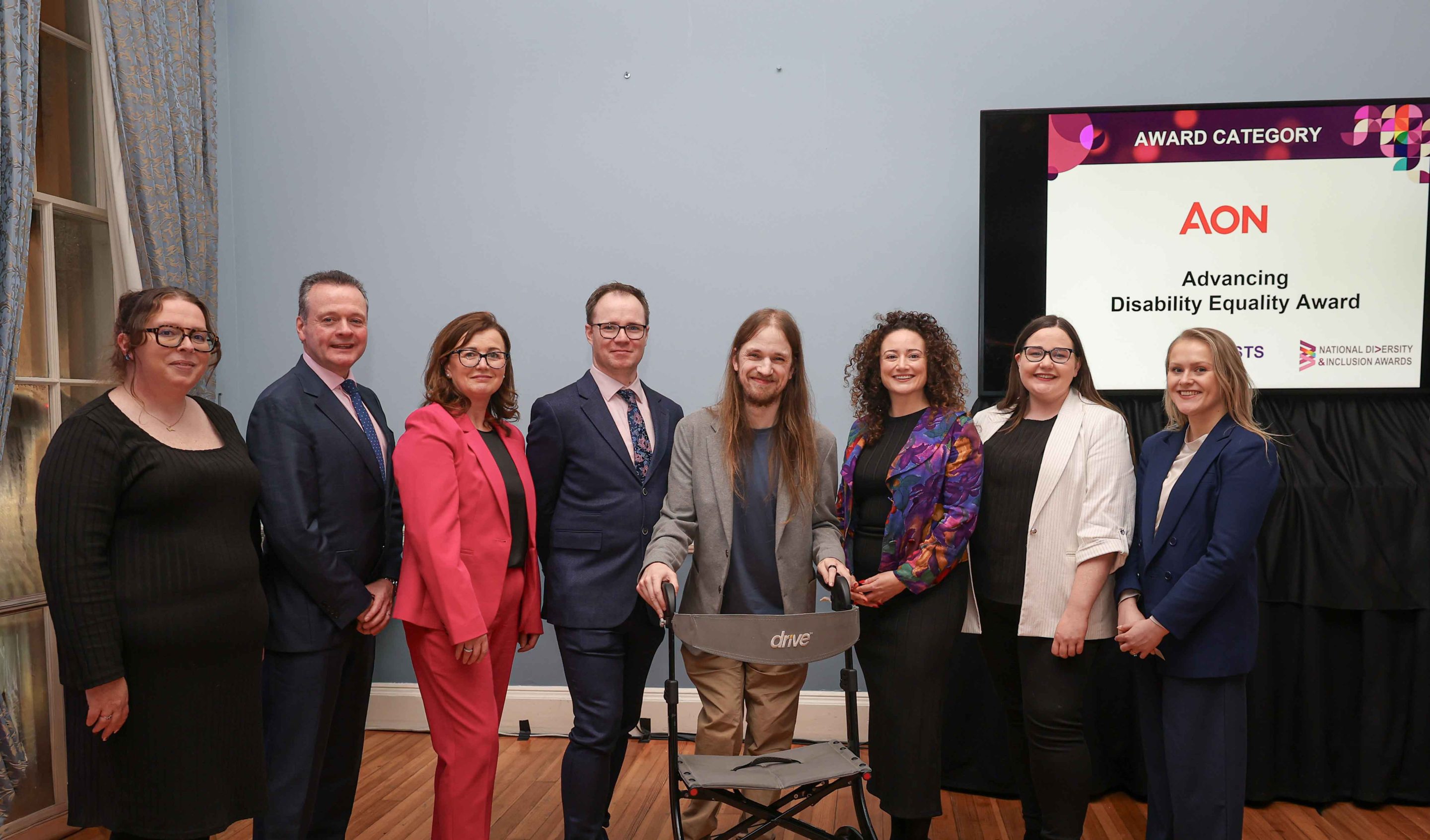 8 smiling people standing shoulder to shoulder