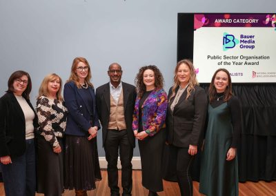 7 smiling people standing shoulder to shoulder