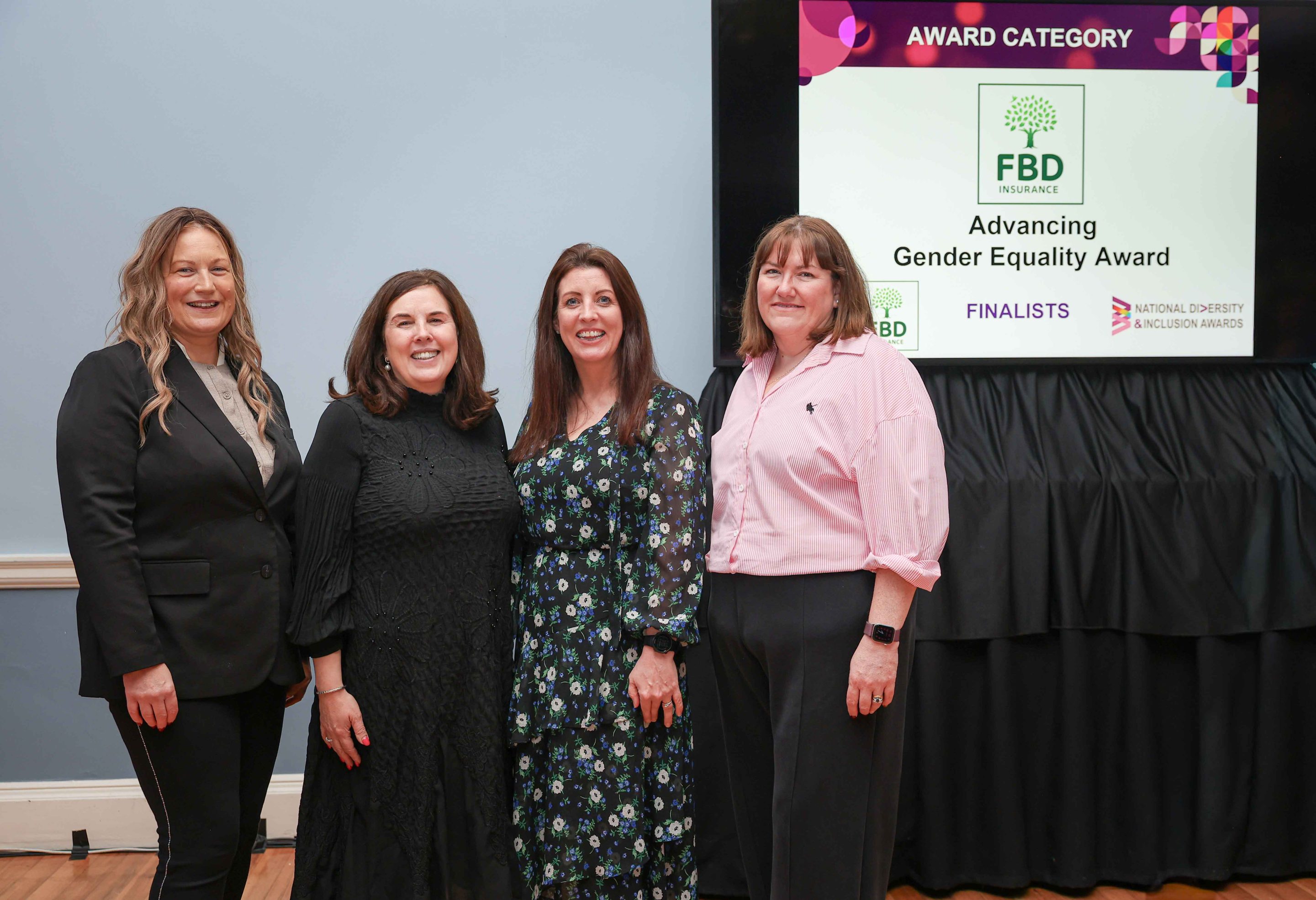 4 smiling people standing shoulder to shoulder