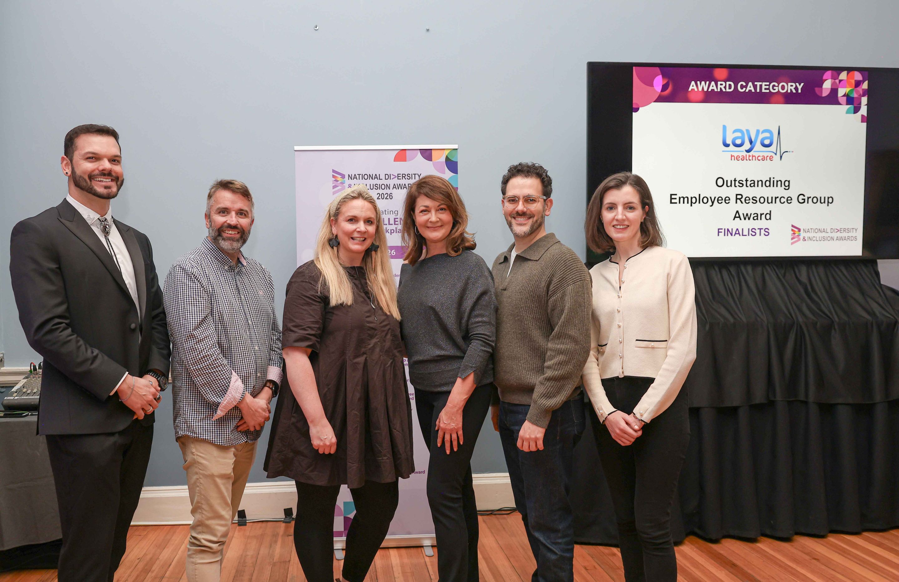 6 smiling people standing shoulder to shoulder