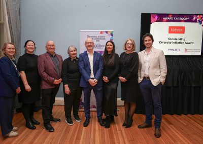 8 smiling people standing shoulder to shoulder