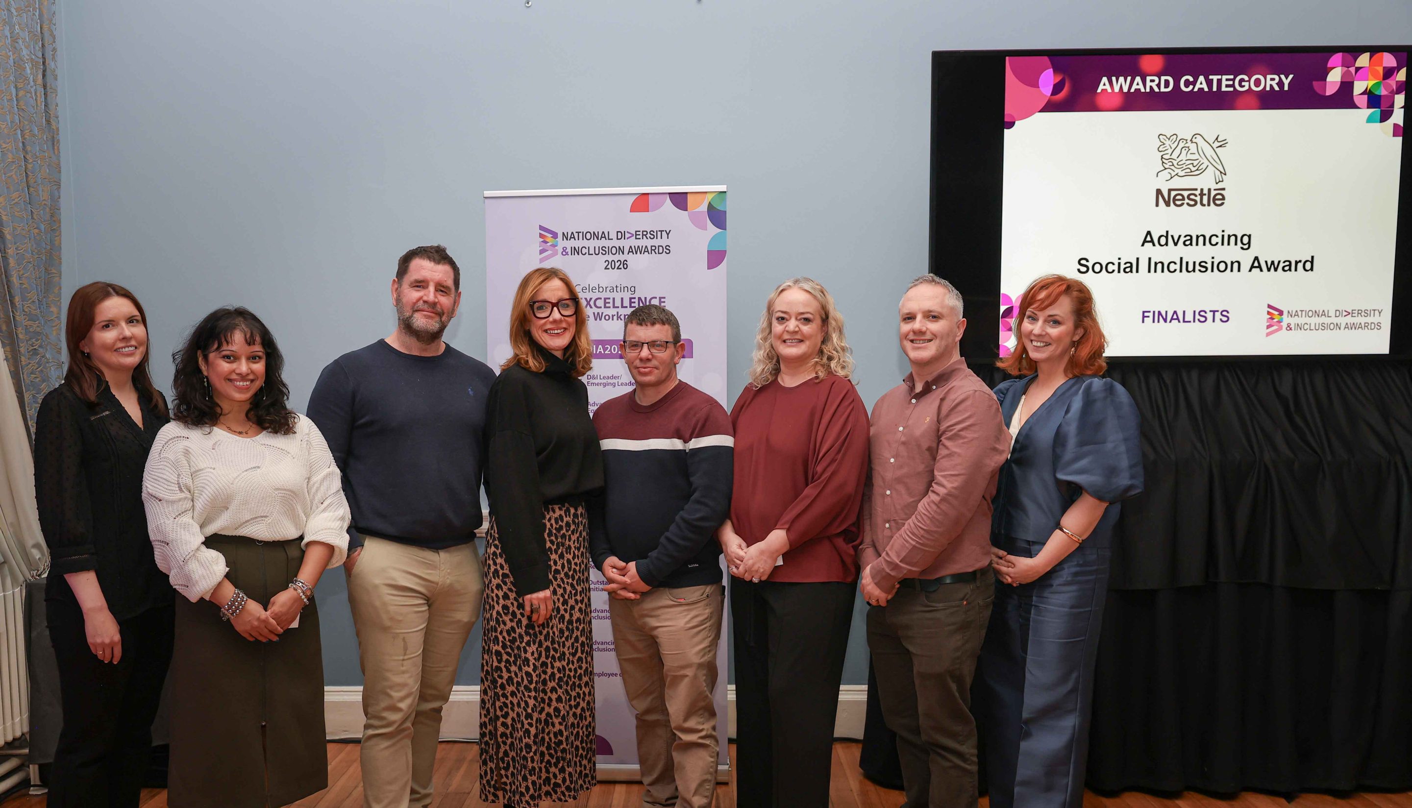 8 smiling people standing shoulder to shoulder