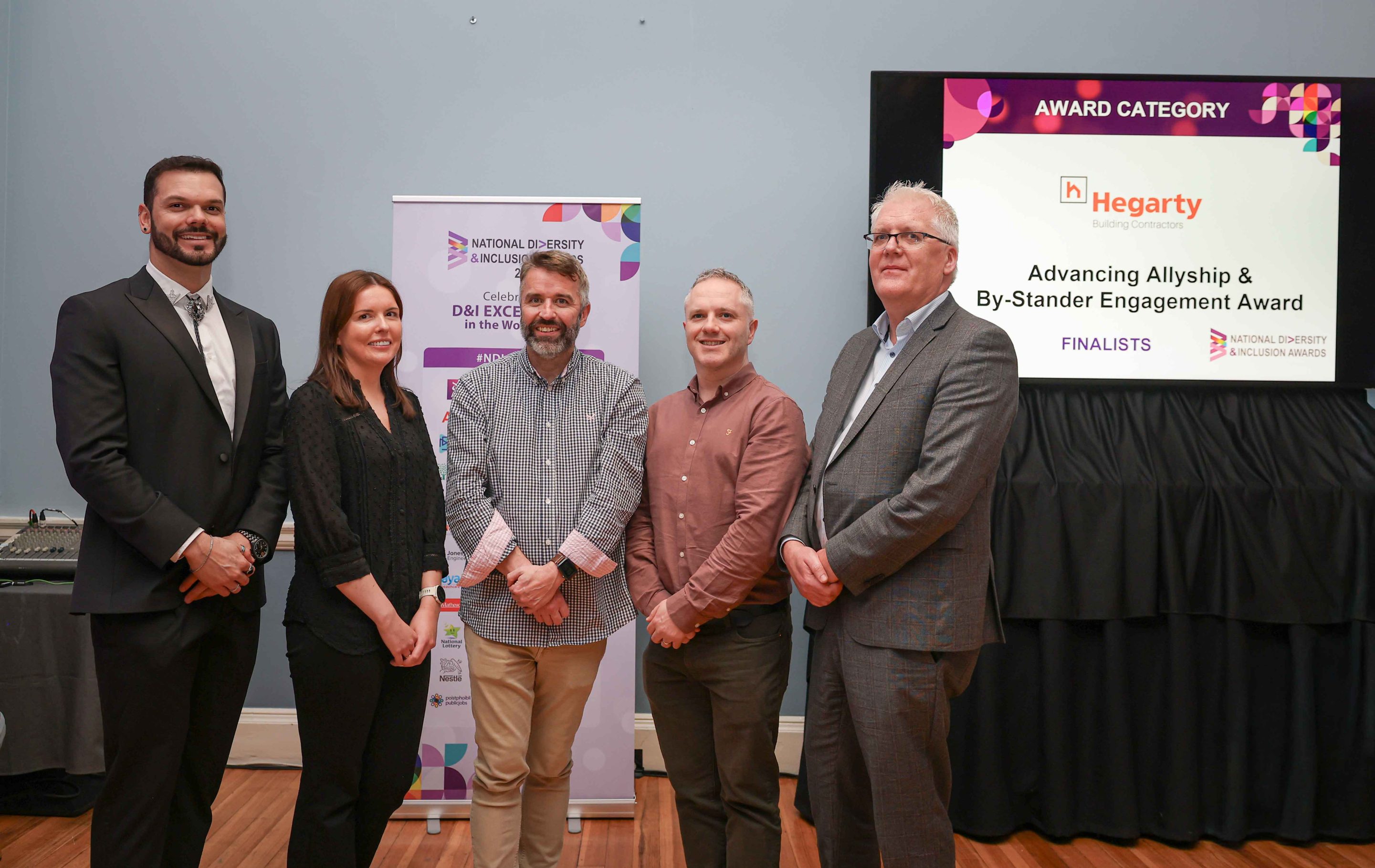 5 smiling people standing shoulder to shoulder