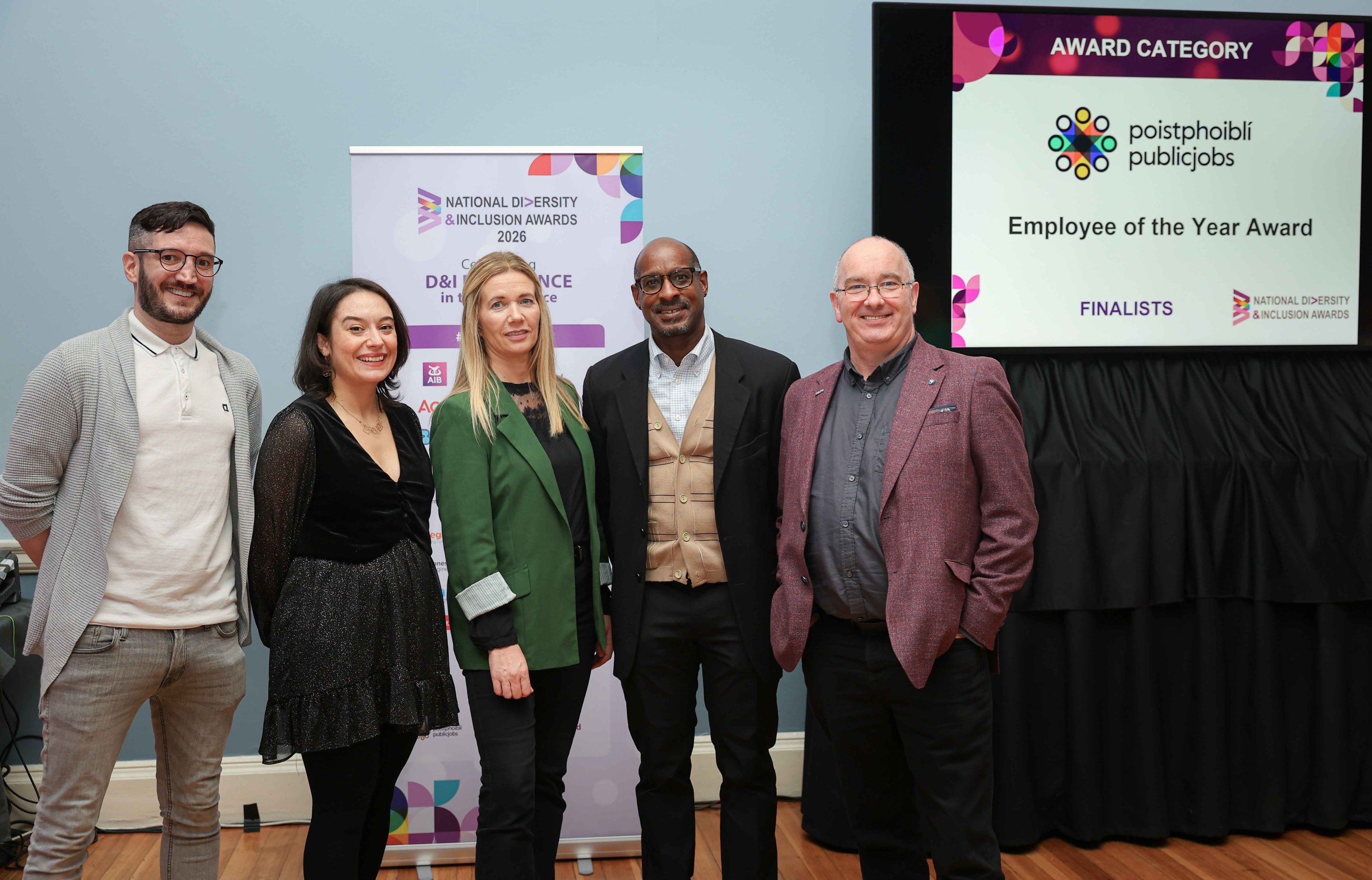 5 smiling people standing shoulder to shoulder