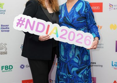 Two smiling people standing shoulder to shoulder