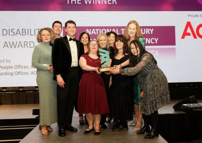 Ten smiling people standing shoulder to shoulder on a stage