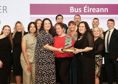 13 smiling people standing shoulder to shoulder on a stage