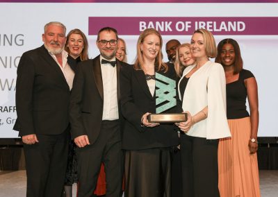 Nine smiling people standing shoulder to shoulder on a stage