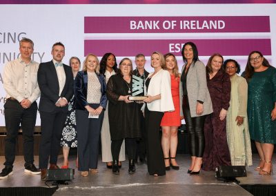 13 smiling people standing shoulder to shoulder on a stage