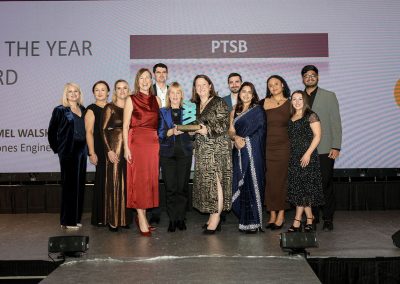 11 smiling people standing shoulder to shoulder on a stage