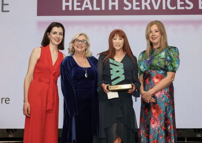Four smiling people standing shoulder to shoulder on a stage