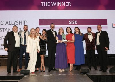 11 smiling people standing shoulder to shoulder on a stage